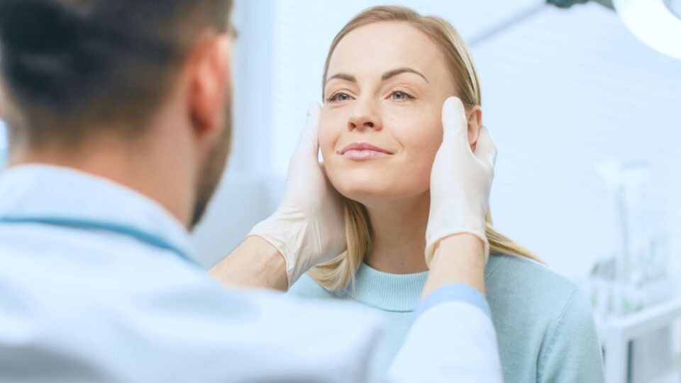 Doctor examining woman's face before treatment in Jackson, MS